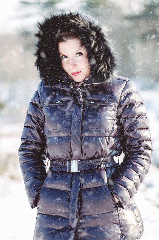 漂亮的年轻时尚的女人摆姿势，在一个阳光明媚的冬天，在公园里走时尚外套