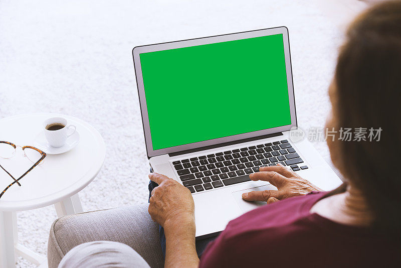 在家里使用绿屏笔记本电脑的资深女性