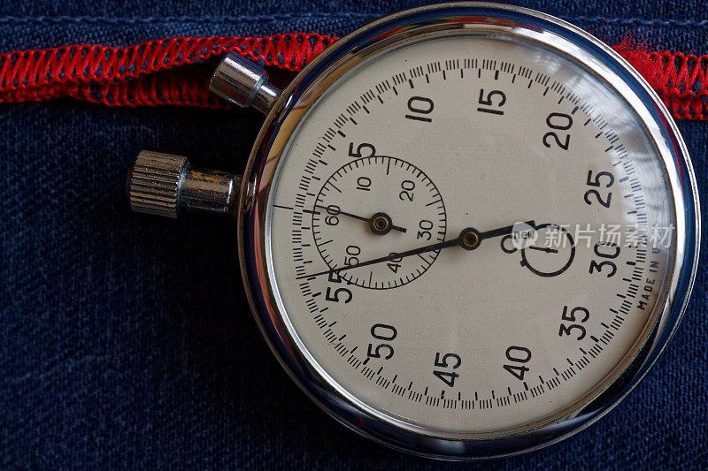 秒表在深蓝色牛仔布背景与红色条，值测量时间，旧时钟箭头分秒精确计时器记录