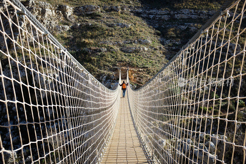 女孩穿过马泰拉峡谷的索桥