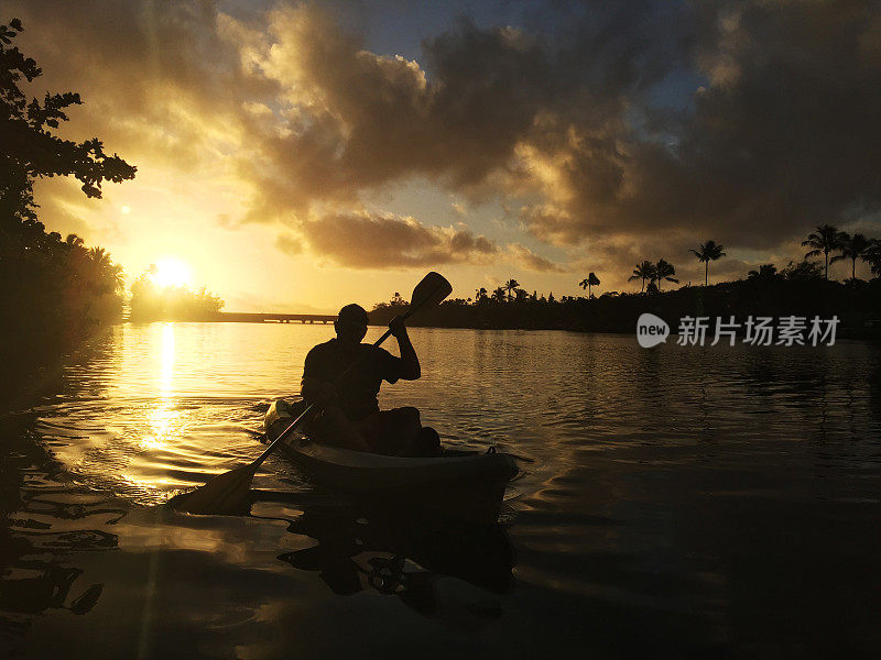 清晨的阳光沐浴在天空中，人们在外陆河上划着皮艇