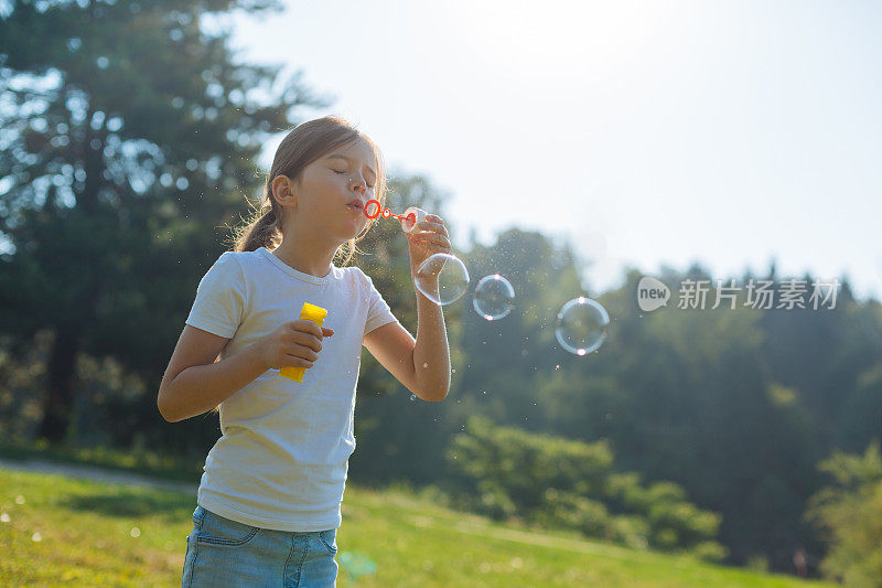 可爱的小女孩在户外吹肥皂泡