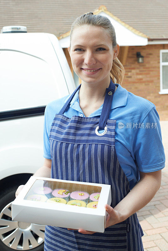 女面包师站在货车旁为家庭送蛋糕