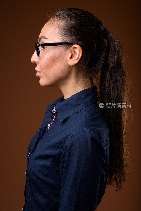 工作室拍摄的年轻美丽的女商人穿着蓝色的衬衫，以彩色的背景