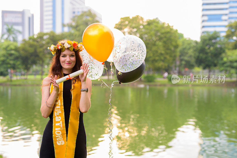 年轻美丽的女子庆祝毕业的肖像在泰国曼谷伦皮尼公园