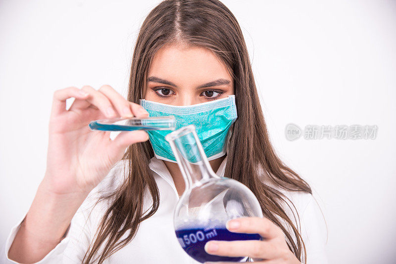 女科学家戴着保护面罩将液体倒入圆形底瓶