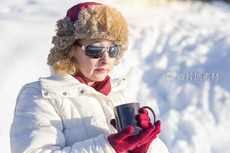 在雪中微笑的女人举着一个杯子的肖像