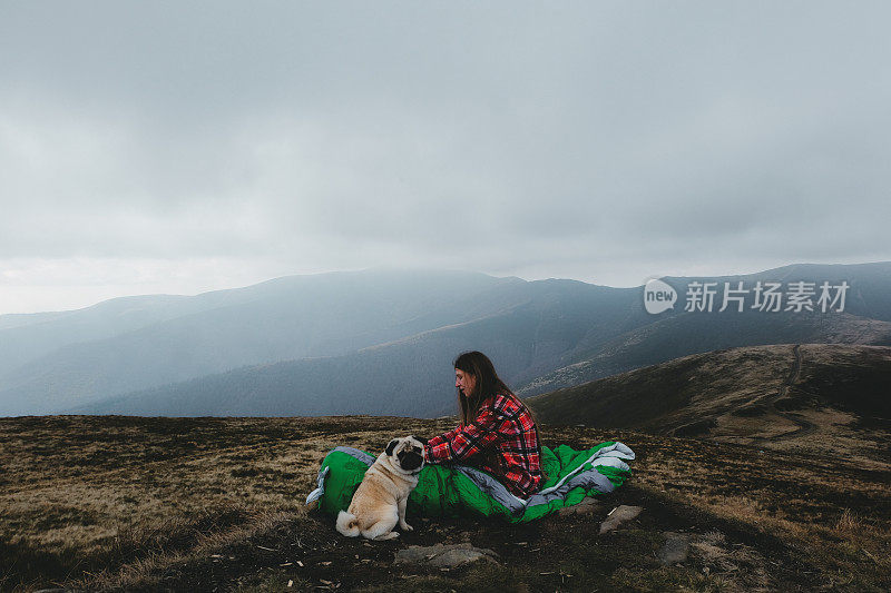 睡袋里的女人和狗在山中醒来