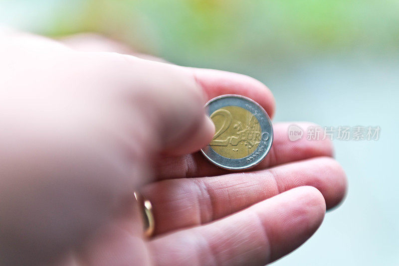 一只手拿着一枚两欧元硬币