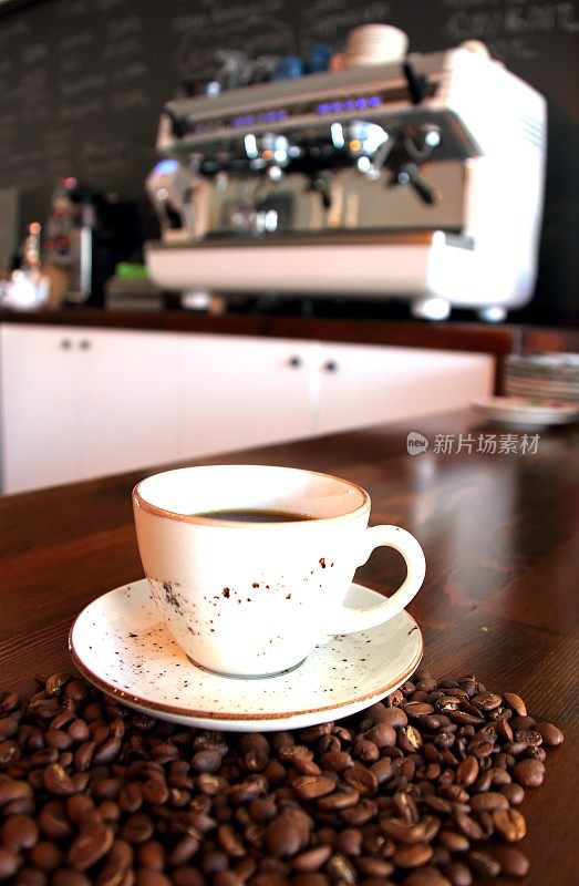 以咖啡豆和现代咖啡机为背景的咖啡杯