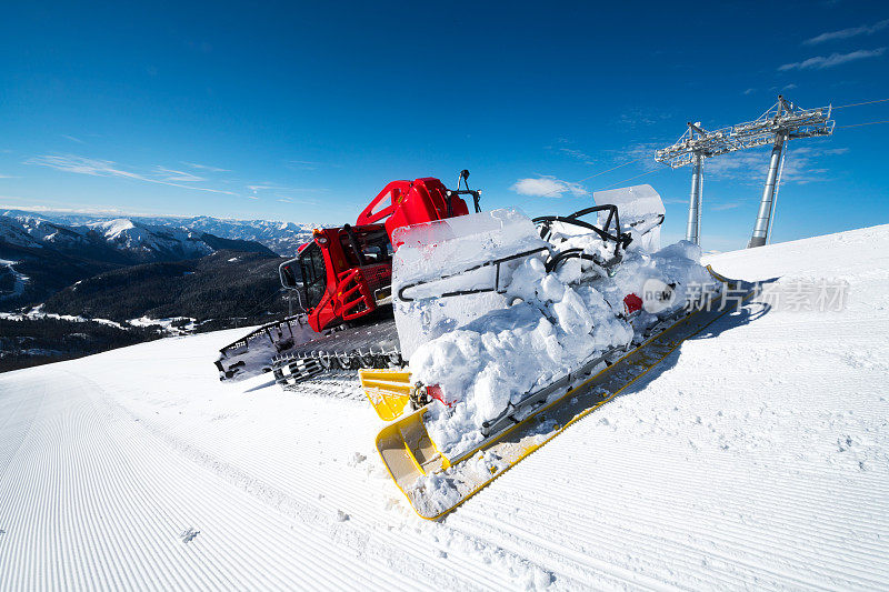 现代红色雪清理雪道上的雪堆在一个阳光明媚的日子在山上