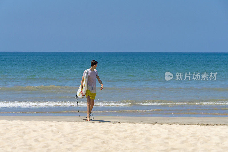 一个年轻人带着冲浪板离开帕卡朗海滩