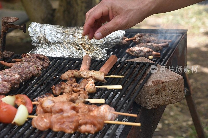 在烧烤架上烧烤食物，用手准备烤肉串