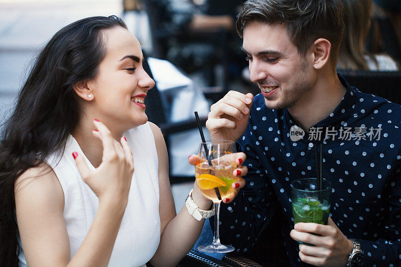 年轻的夫妇笑着喝着鸡尾酒