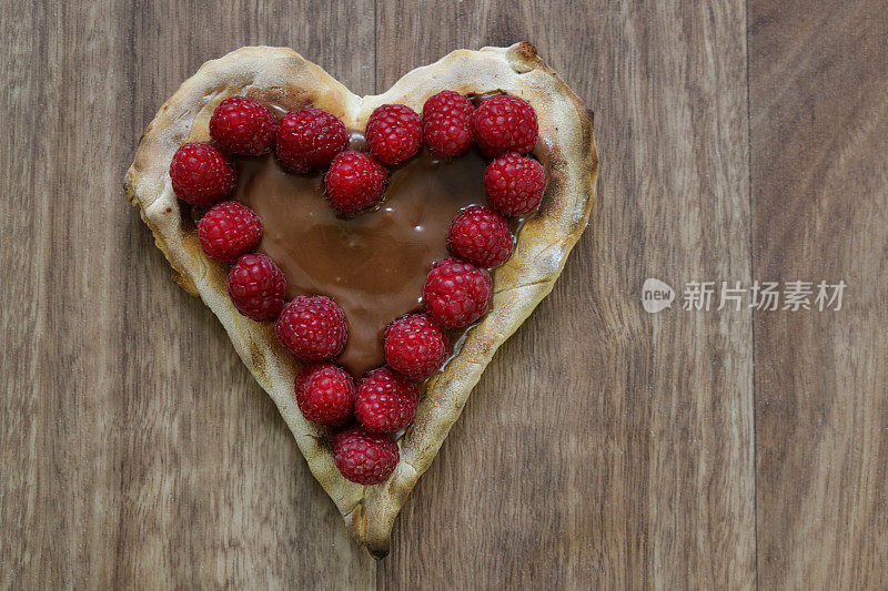 心形甜点巧克力披萨配上新鲜的树莓和巧克力榛子，心形甜点披萨配上新鲜的树莓，这是情侣们在2月14日情人节晚餐后吃的浪漫甜点布丁蛋糕