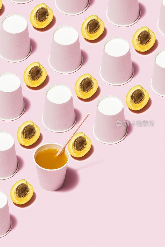 桃汁和白色纸杯平铺在粉红色的背景上