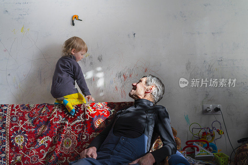 70岁的老人，爷爷，和她两岁的孙女在经济适用房玩。