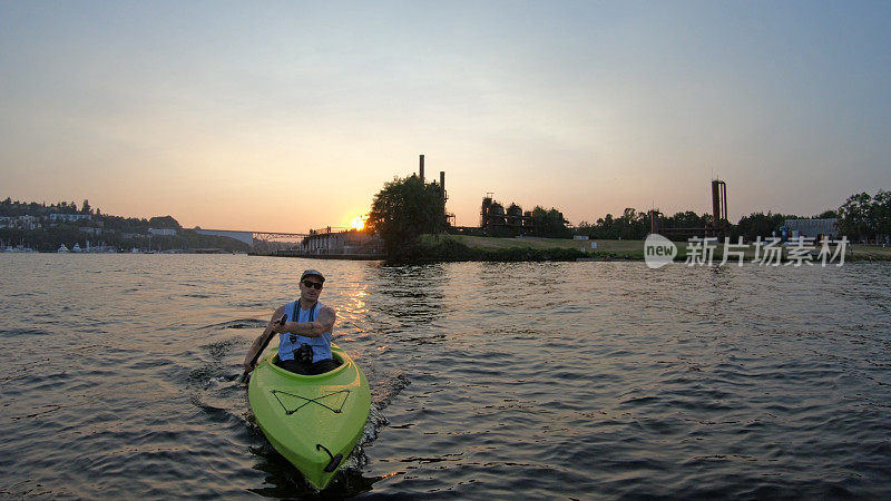 皮划艇摄影师在日落时在湖中划桨