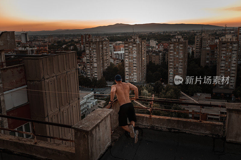 赤裸上身的男人在城市楼顶锻炼
