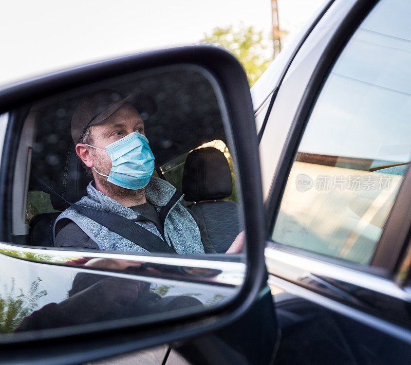 汽车司机戴着防护面罩检查他的镜子