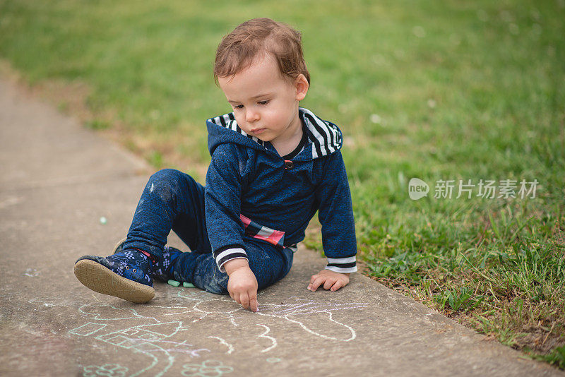 孩子独自在外面玩，用粉笔在混凝土上画画