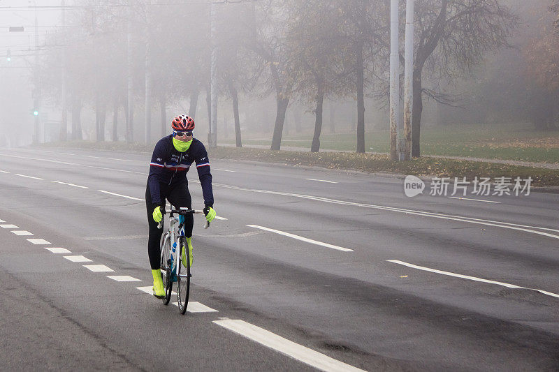 有雾的早晨，骑自行车的人经过空无一人的城市街道