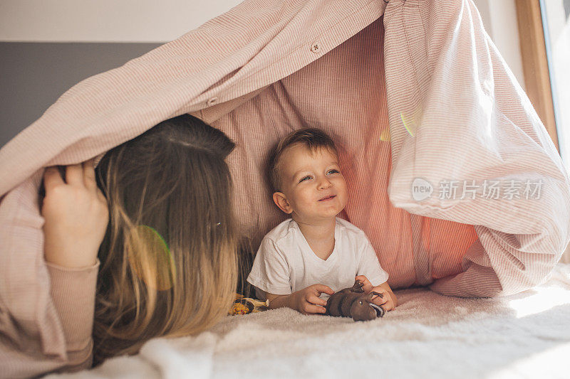 怀孕的妈妈和年幼的儿子在卧室里玩耍