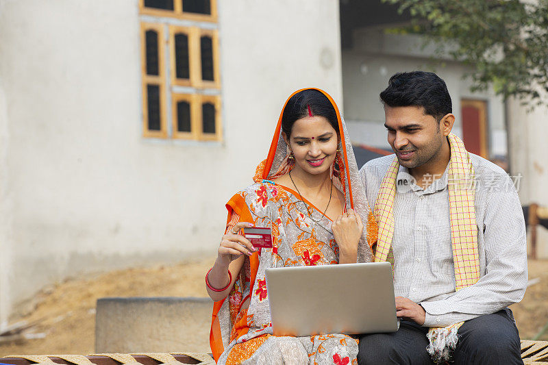 印度夫妇使用笔记本电脑在村庄库存照片