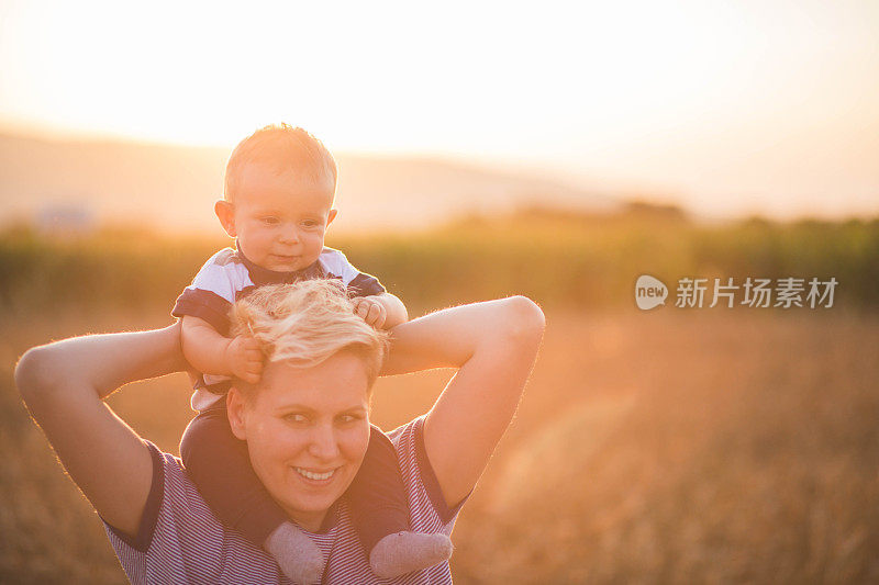 女人抱着孩子在金黄的麦穗地里种庄稼。