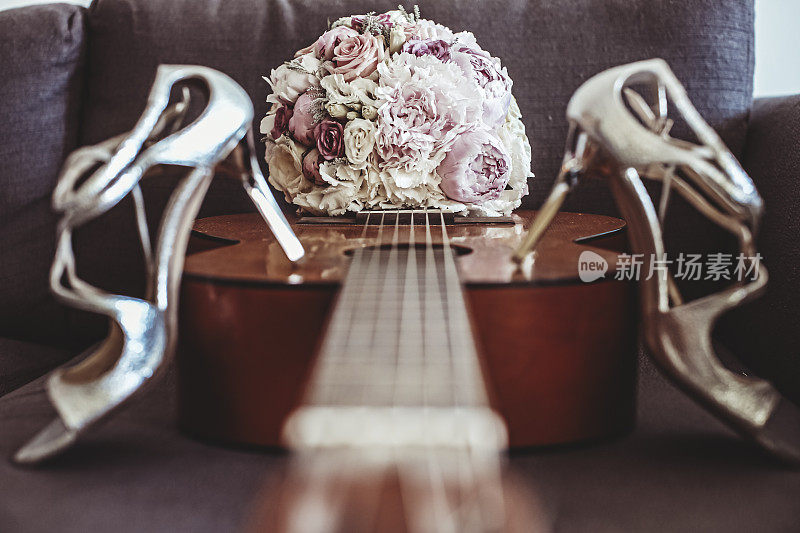 新娘的白色凉鞋放在古典吉他上