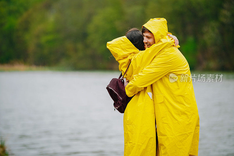 一对穿着雨衣的幸福夫妇站在码头上