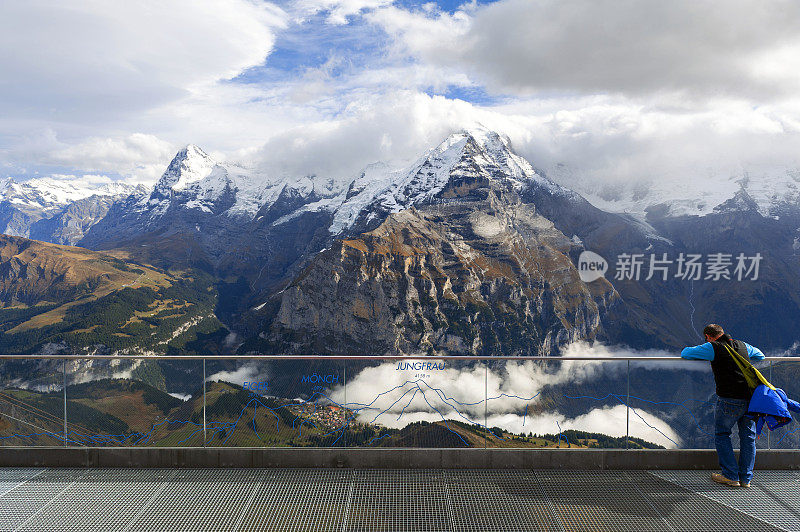 一名游客在位于瑞士柏格索道站的观景台上观察少女峰、艾格尔峰和伯尔尼阿尔卑斯山的蒙奇峰