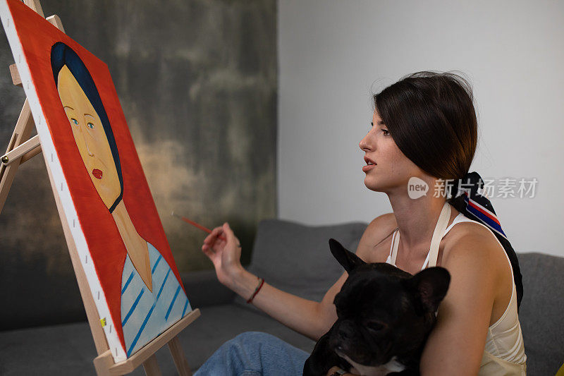 一个年轻女子在画画，腿上抱着一只狗