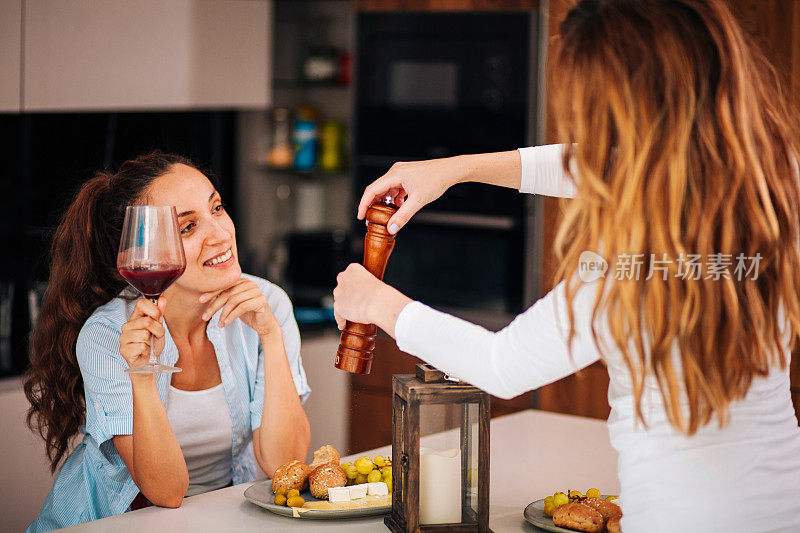 两个女人在家里享用开胃菜和酒的照片