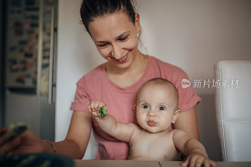 母亲用勺子喂她的婴儿儿子