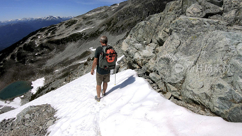 徒步旅行者沿着积雪的山坡跑下去