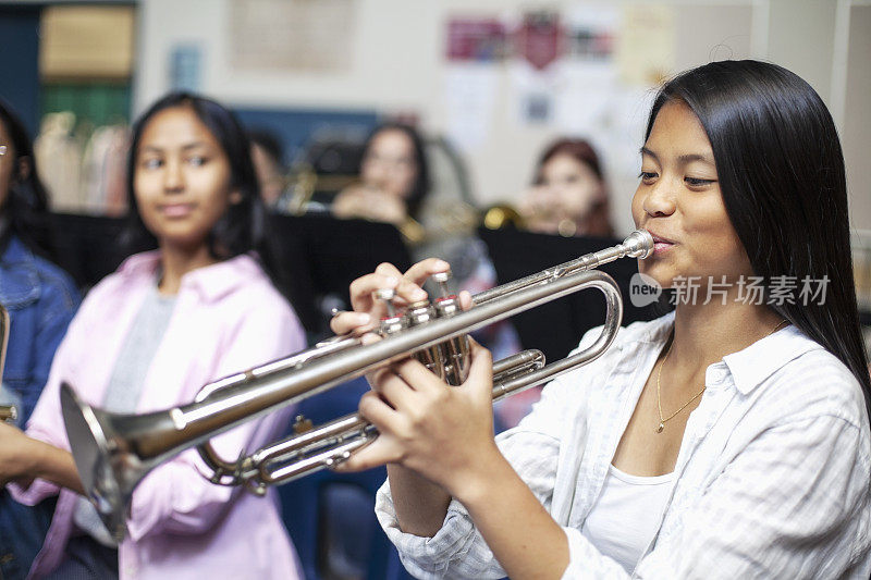 十几岁的亚裔菲律宾女孩在音乐课上吹小号