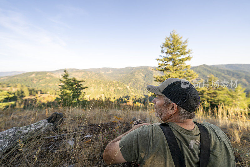 打猎时，一个人坐在长满森林的山坡上