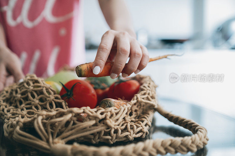 年轻女子从桌子上的可重复使用的购物袋中整理水果和蔬菜的镜头