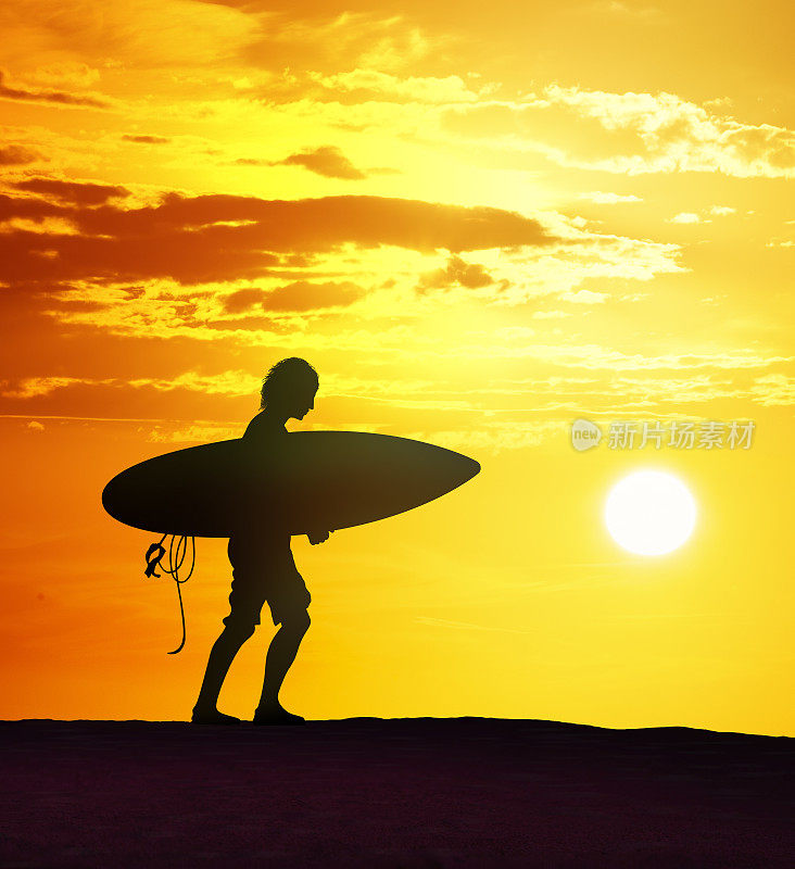 冲浪者在美丽的日落与冲浪板散步