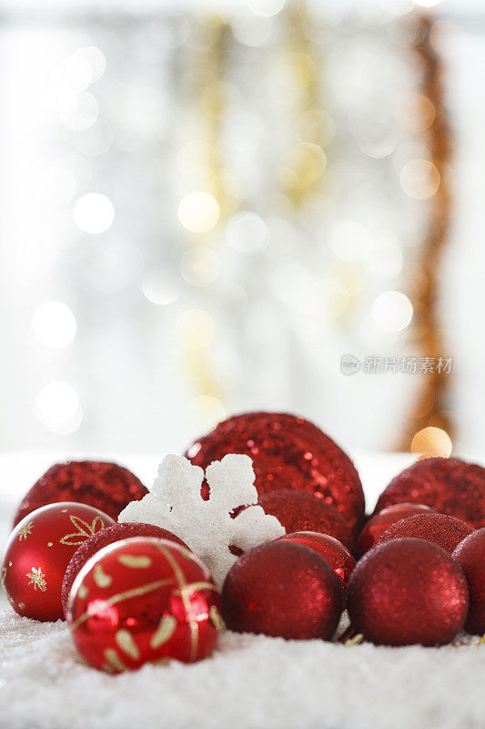 圣诞背景上点缀着闪闪发光的红色装饰品和雪花