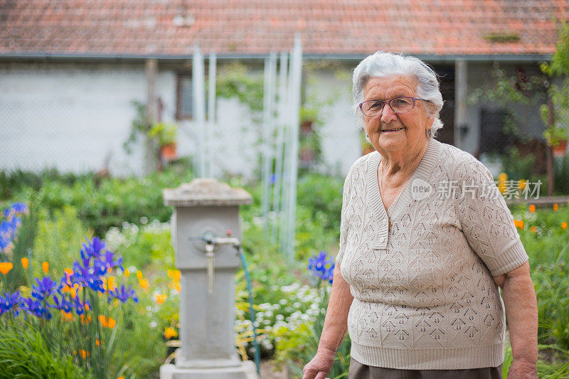 年长的女人在花园里带着花