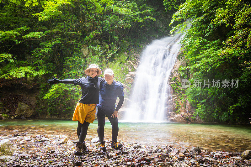 两个女徒步旅行者在大瀑布边享受大自然