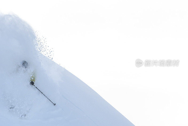 偏远地区的滑雪者从雪山山脊上滑下来