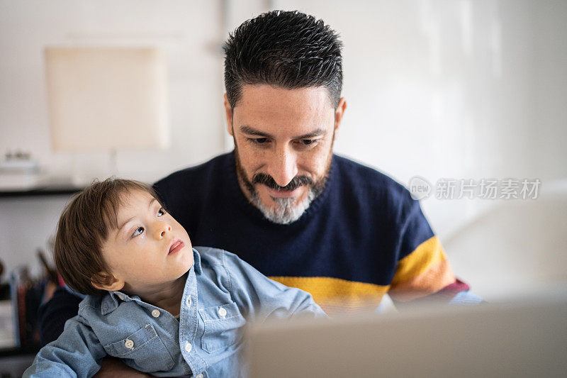 在家里工作的成熟男人带着年幼的儿子——有特殊需要的儿子