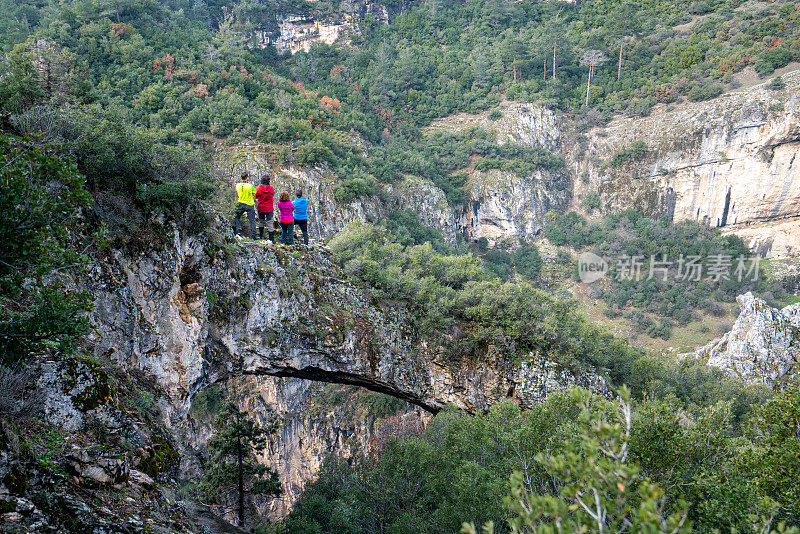 登山队伍站在岩石拱门在峡谷，看着美丽的风景，森林，峡谷