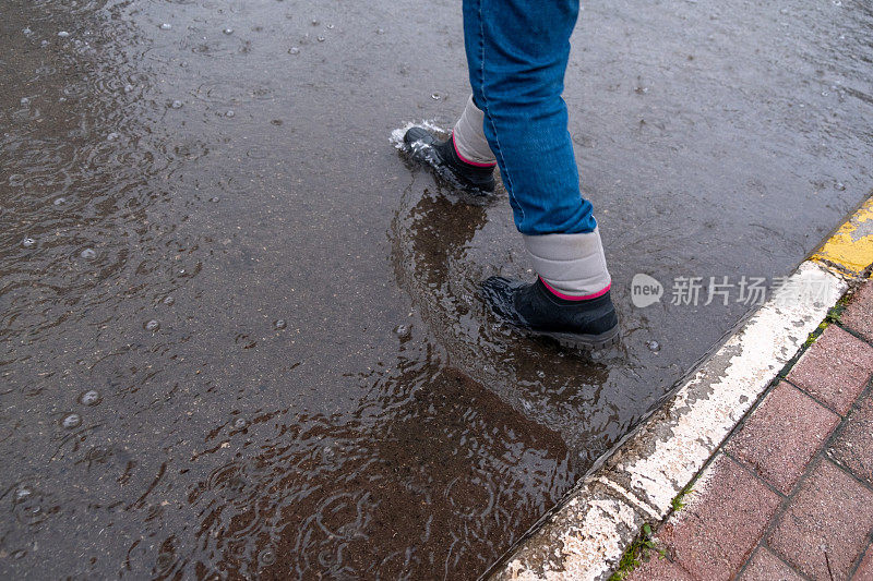 在室内天气，穿着近距离靴子的雨脚正踩在高水位的脚上。过马路。