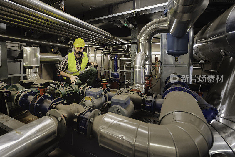 在工厂的生产线上，身着制服的技术员对锅炉罐和液体管道进行压片检查和控制