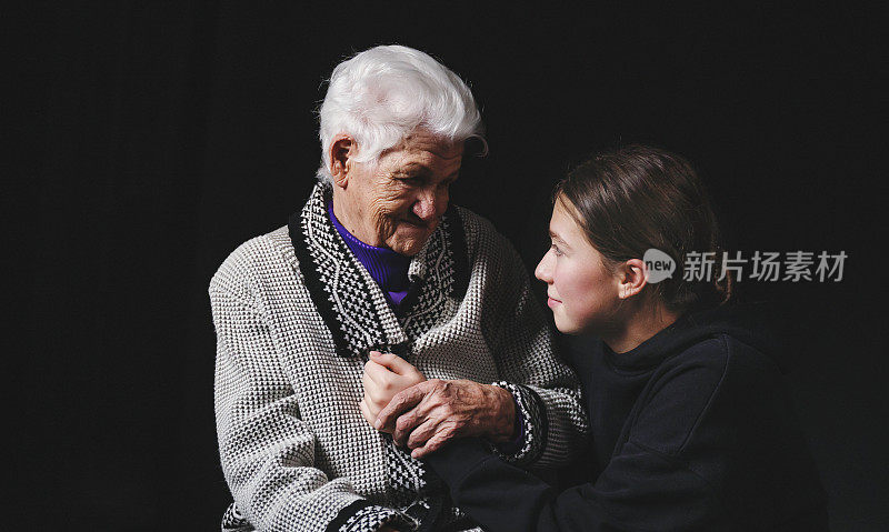 一位年长的妇女和她成年的孙女坐在一起