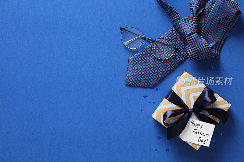 父亲节背景有礼品盒、领带、蓝色眼镜。祝父亲节快乐贺卡设计。